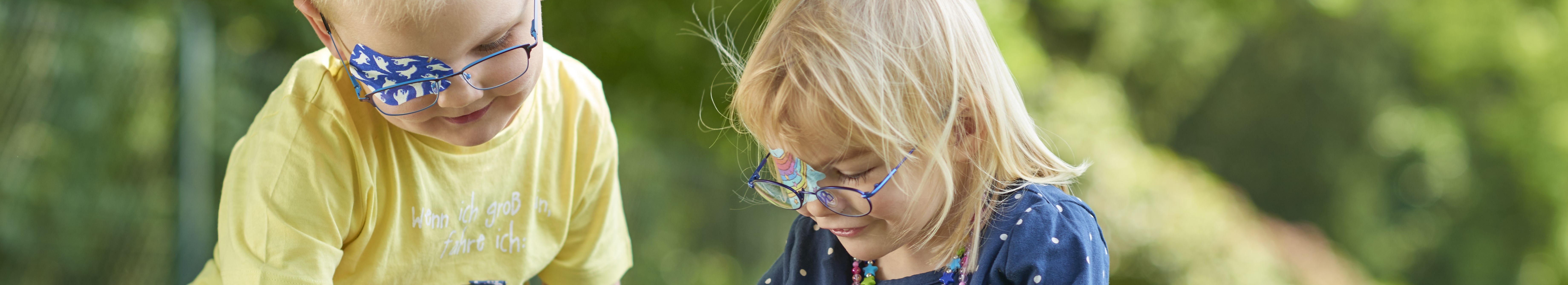 Kopfgrafik spielende Kinder mit ORTOPAD® Augenpflaster Gespenster und Regenbogen