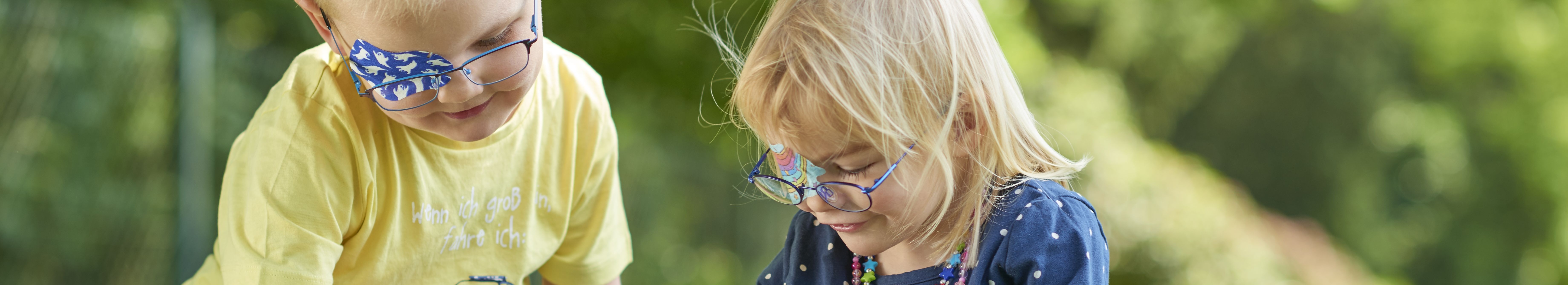 Kopfgrafik spielende Kinder mit ORTOPAD® Augenpflaster Gespenster und Regenbogen