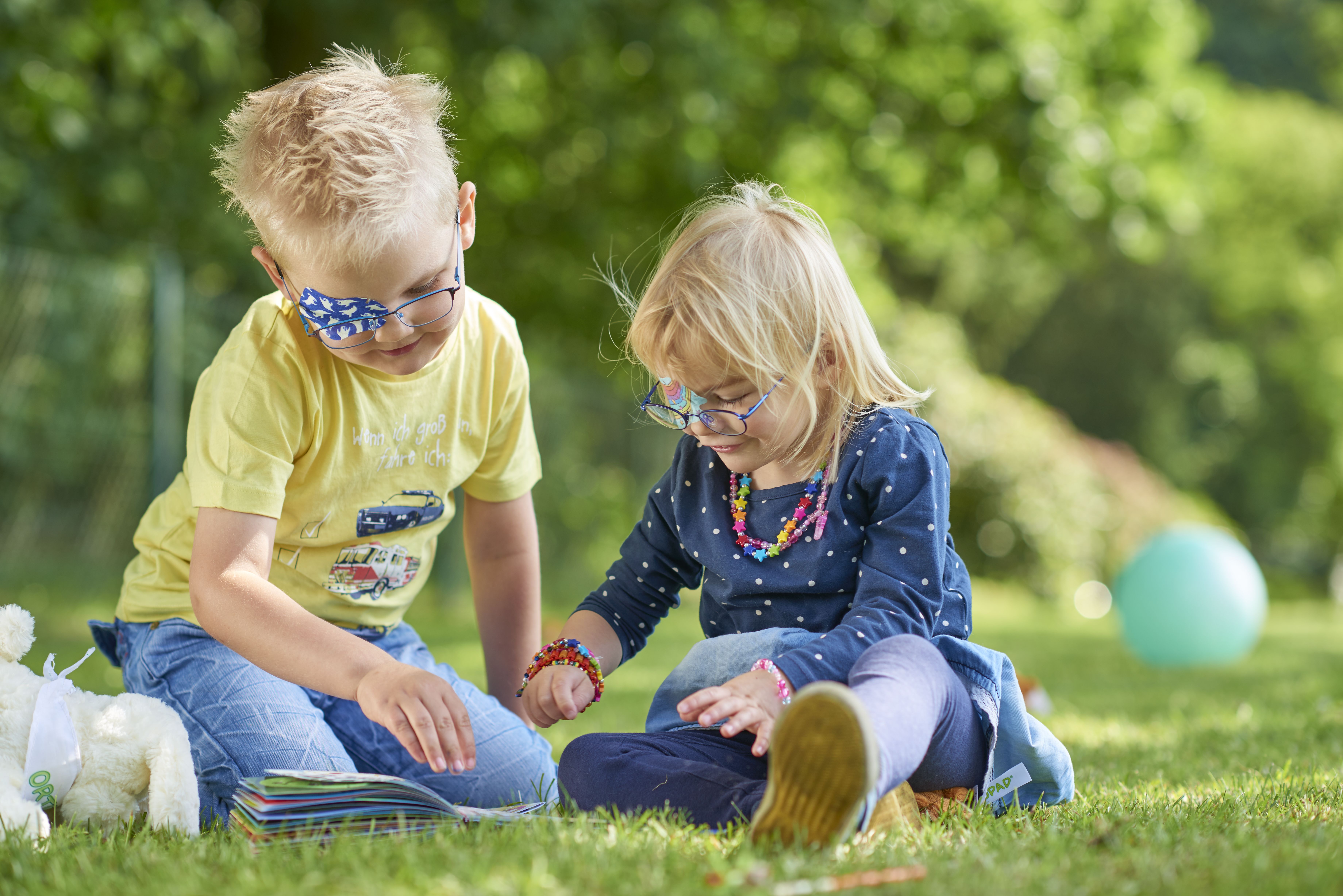 Kopfgrafik spielende Kinder mit ORTOPAD® Augenpflaster Gespenster und Regenbogen